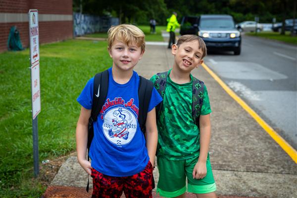 two boys walking on sidewalk